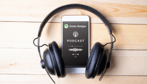 Headphones on a table with a phone and the green badger logo - podcasts